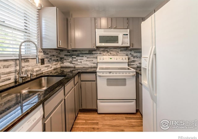 kitchen with gray cabinetry, sink, white appliances, and backsplash