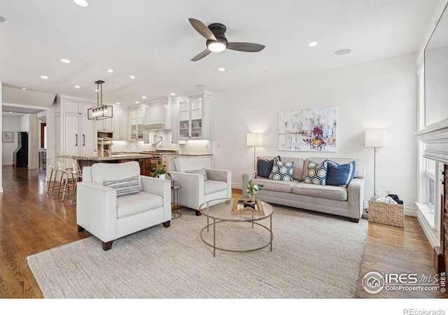 living room with wood finished floors, ceiling fan, recessed lighting, baseboards, and a fireplace