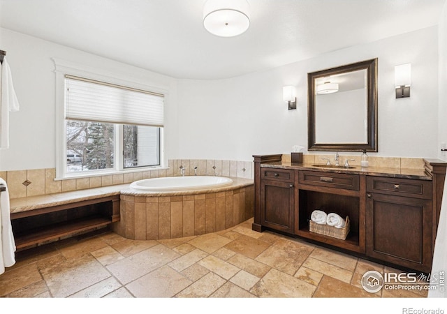 full bath with stone tile flooring, vanity, and a garden tub