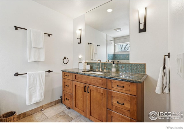 bathroom with baseboards, vanity, and decorative backsplash