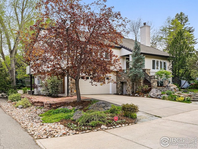 view of front facade featuring driveway, stone siding, a garage, stairs, and a chimney
