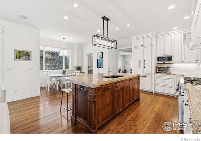 kitchen with a sink, stainless steel appliances, dark wood-style floors, white cabinetry, and tasteful backsplash