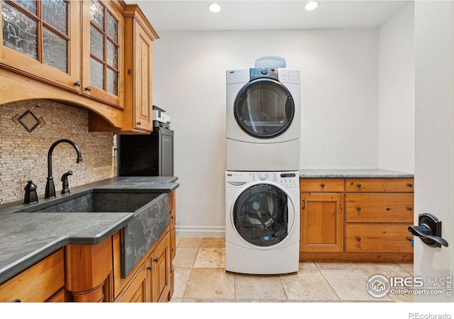 laundry room with stacked washer / drying machine, cabinet space, baseboards, and recessed lighting