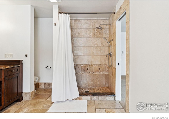 full bathroom with tiled shower, toilet, and stone tile floors