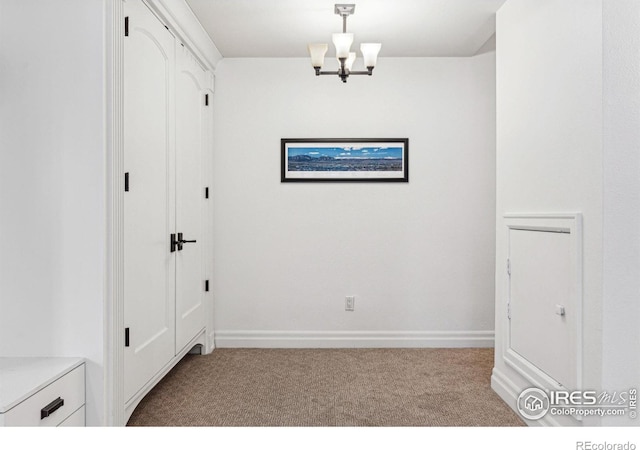 corridor featuring carpet floors, a chandelier, and baseboards