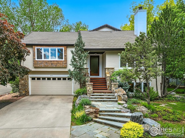 view of front of house featuring concrete driveway, a garage, stone siding, a chimney, and a tile roof