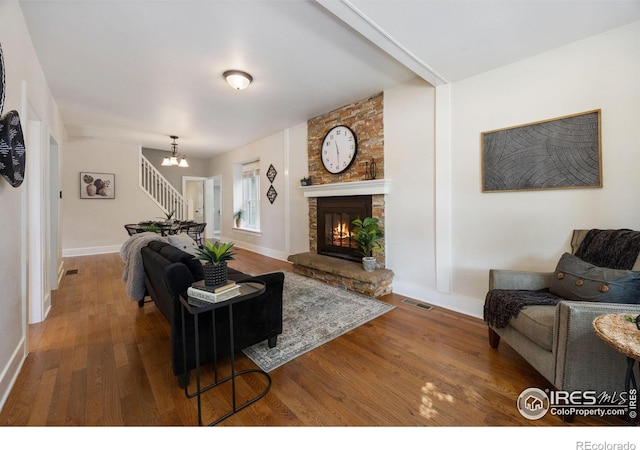 living room with a fireplace, a notable chandelier, and wood-type flooring