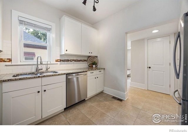 kitchen featuring sink, stainless steel appliances, light stone counters, white cabinets, and decorative backsplash