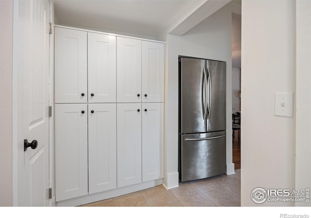 kitchen featuring stainless steel fridge and white cabinets