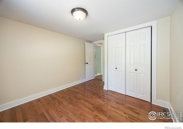 unfurnished bedroom with dark hardwood / wood-style floors and a closet