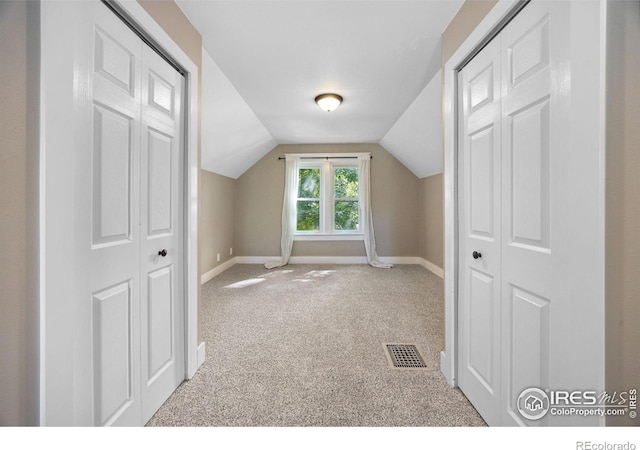 bonus room with lofted ceiling and light colored carpet