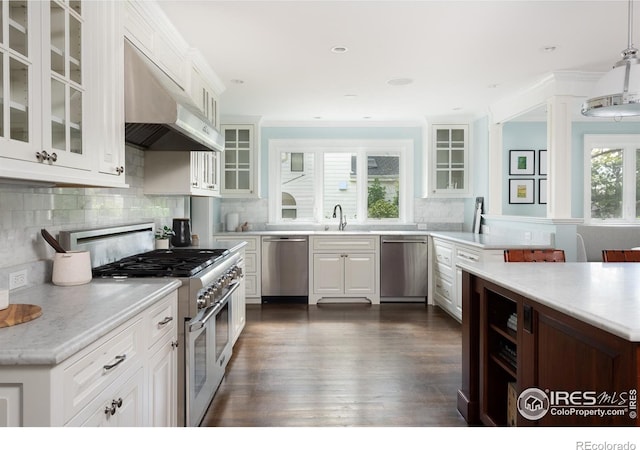 kitchen featuring extractor fan, decorative light fixtures, white cabinets, and appliances with stainless steel finishes