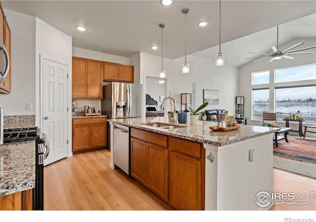 kitchen with sink, light stone counters, an island with sink, pendant lighting, and stainless steel appliances