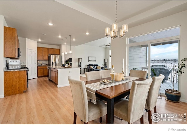 dining room featuring ceiling fan with notable chandelier and light hardwood / wood-style flooring