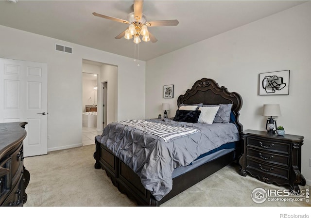 bedroom featuring ensuite bathroom, light colored carpet, and ceiling fan