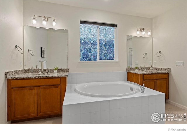 bathroom featuring tile patterned flooring, vanity, and a relaxing tiled tub