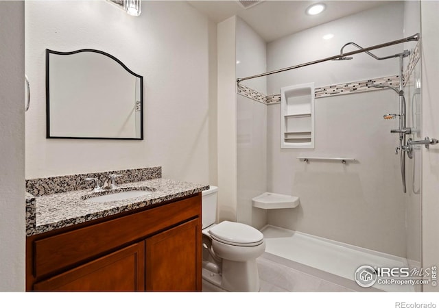 bathroom with tile patterned flooring, vanity, walk in shower, and toilet