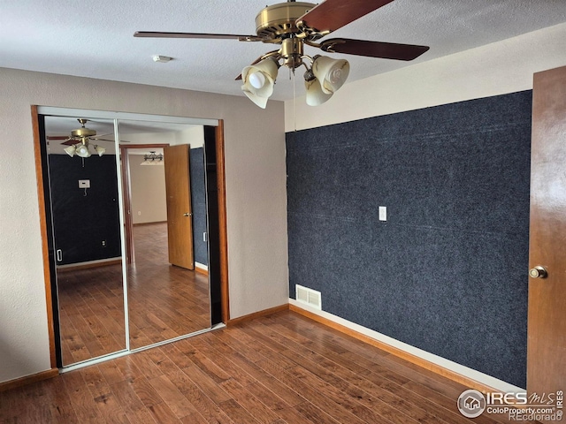 unfurnished bedroom with ceiling fan, wood-type flooring, a closet, and a textured ceiling