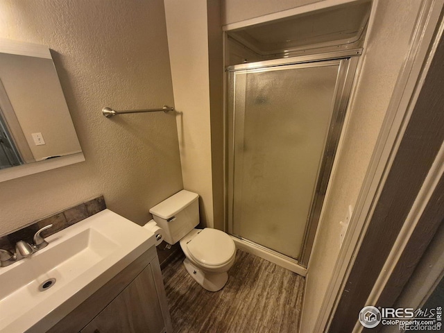 bathroom with vanity, hardwood / wood-style floors, a shower with door, and toilet