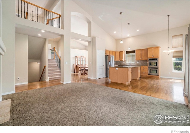 kitchen with appliances with stainless steel finishes, a center island, high vaulted ceiling, and hanging light fixtures