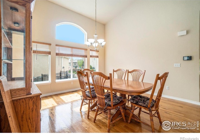 dining area featuring an inviting chandelier, high vaulted ceiling, and light wood-type flooring