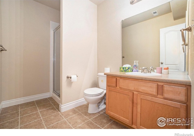 bathroom featuring tile patterned flooring, vanity, toilet, and a shower with shower door