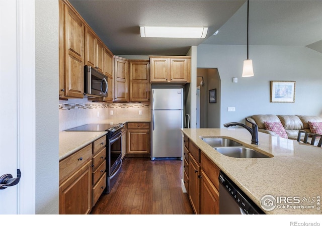 kitchen featuring sink, appliances with stainless steel finishes, light stone counters, dark hardwood / wood-style flooring, and decorative light fixtures