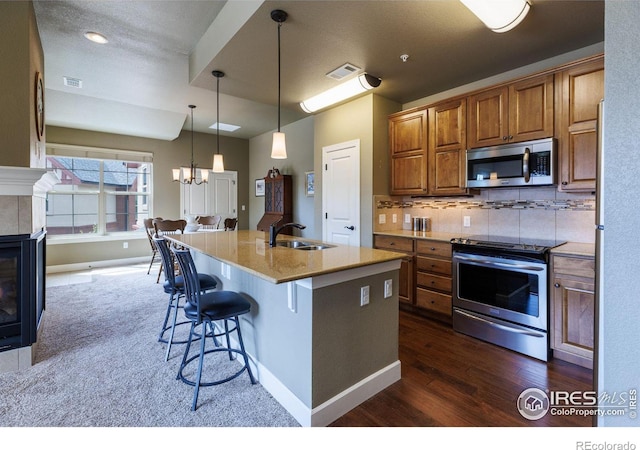 kitchen featuring sink, a kitchen breakfast bar, stainless steel appliances, a kitchen island with sink, and decorative backsplash