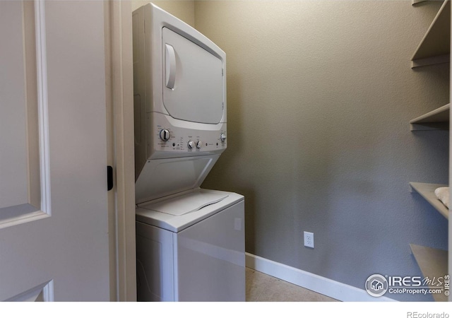 laundry area with stacked washer and clothes dryer and light tile patterned floors