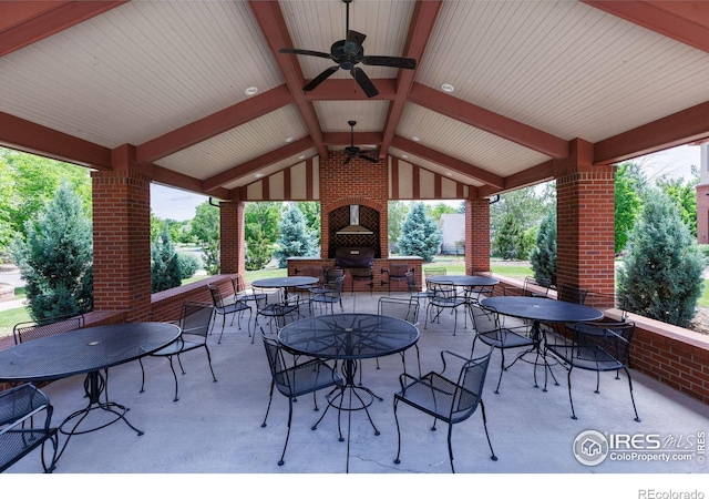 view of patio featuring an outdoor brick fireplace, a gazebo, and ceiling fan