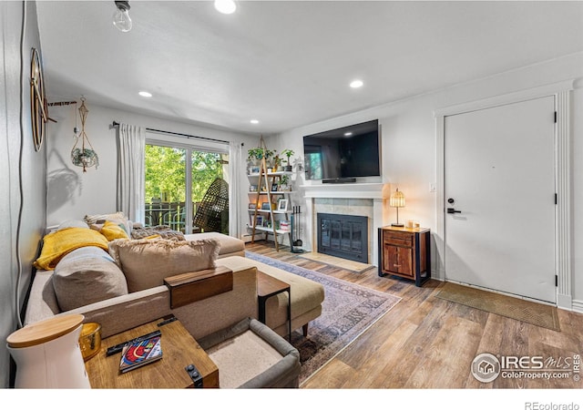 living room with a tiled fireplace and hardwood / wood-style floors