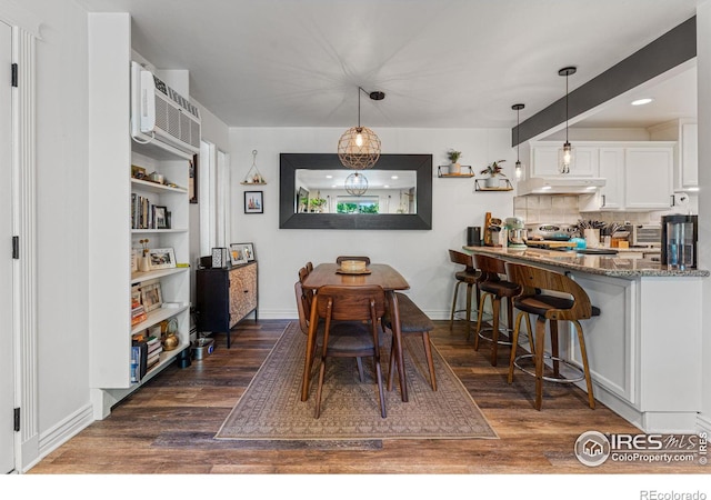 dining area featuring a wall mounted air conditioner and dark hardwood / wood-style floors