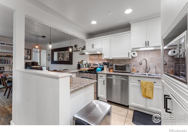 kitchen featuring decorative light fixtures, white cabinetry, sink, kitchen peninsula, and stainless steel appliances