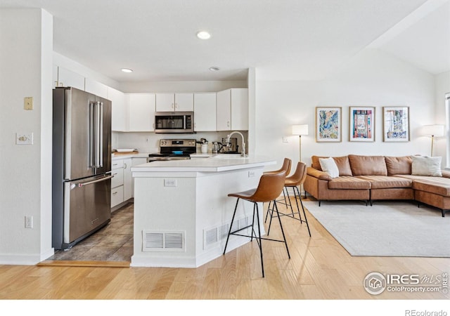 kitchen featuring sink, a breakfast bar, stainless steel appliances, white cabinets, and kitchen peninsula