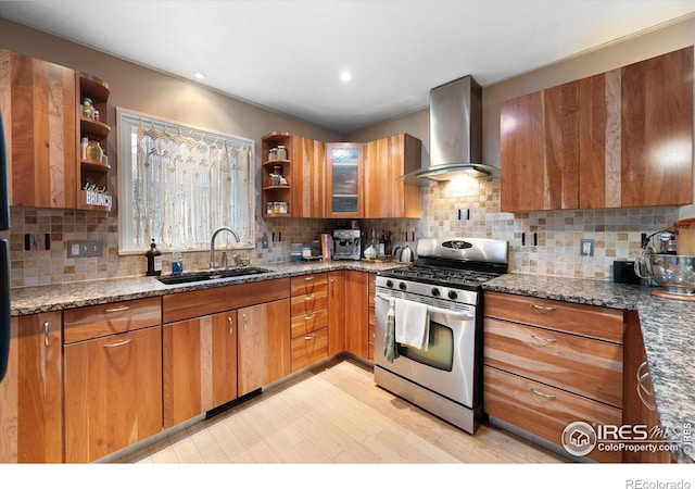 kitchen featuring sink, dark stone countertops, tasteful backsplash, stainless steel gas range oven, and wall chimney exhaust hood