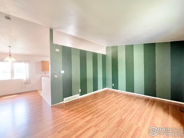 unfurnished room featuring vaulted ceiling and light hardwood / wood-style floors