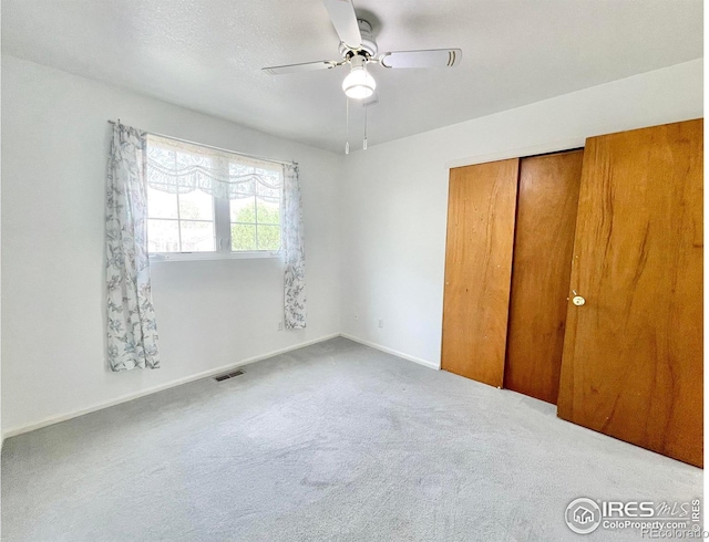 unfurnished bedroom with ceiling fan, carpet flooring, and a closet