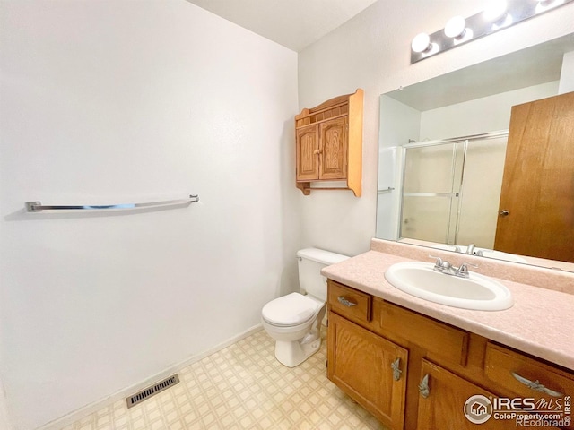 bathroom featuring vanity, a shower with shower door, and toilet