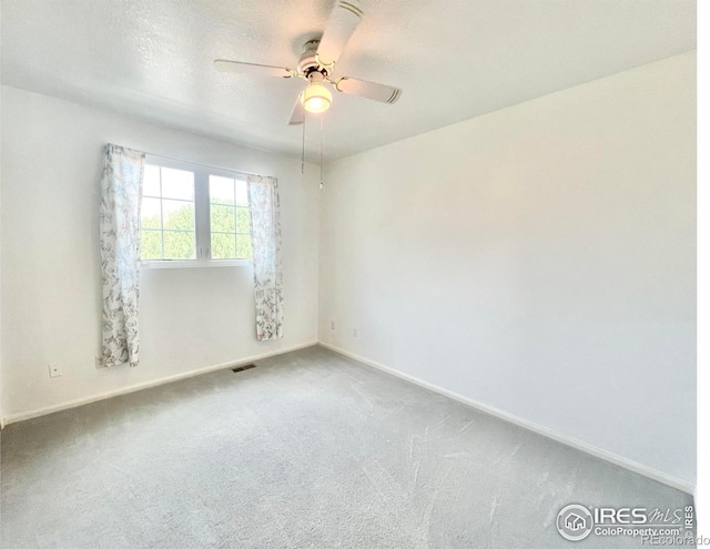 carpeted spare room featuring ceiling fan and a textured ceiling