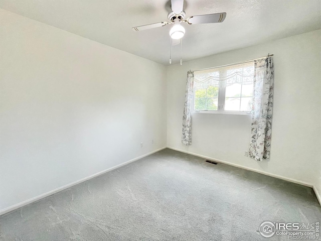 empty room featuring ceiling fan and carpet