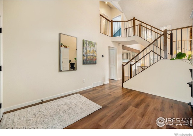 entrance foyer with hardwood / wood-style flooring and high vaulted ceiling