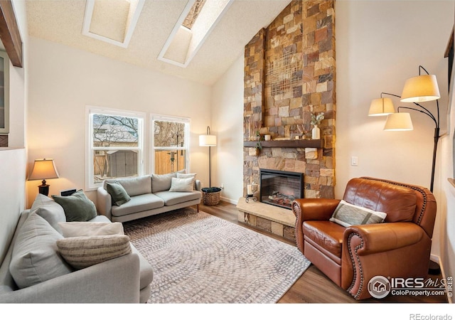 living room with hardwood / wood-style flooring, a stone fireplace, high vaulted ceiling, and a textured ceiling