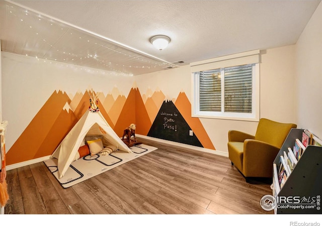 game room featuring hardwood / wood-style floors and a textured ceiling