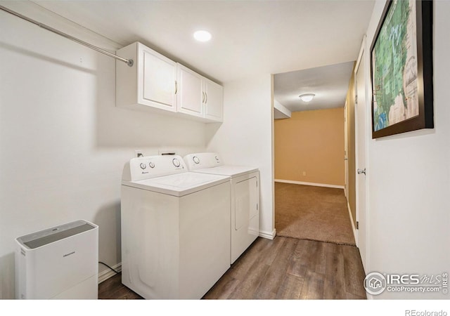 clothes washing area featuring dark hardwood / wood-style flooring, washer and clothes dryer, and cabinets