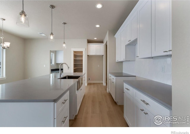 kitchen featuring a spacious island, white cabinetry, sink, and pendant lighting