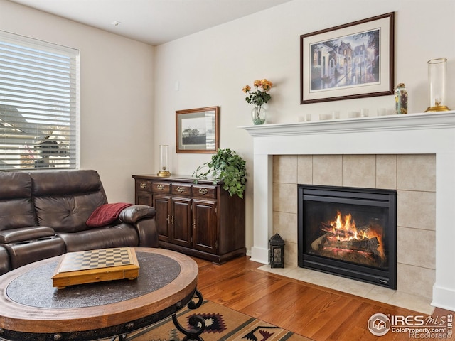 living room featuring a tiled fireplace and light wood-type flooring