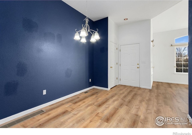 interior space with an inviting chandelier, hardwood / wood-style floors, and lofted ceiling