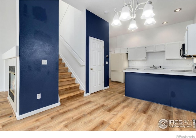 kitchen featuring sink, decorative light fixtures, white fridge, white cabinets, and stove