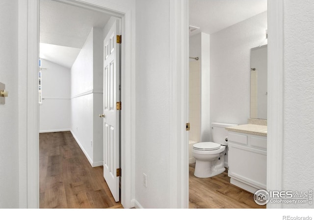 full bathroom featuring toilet, tub / shower combination, vaulted ceiling, vanity, and hardwood / wood-style flooring