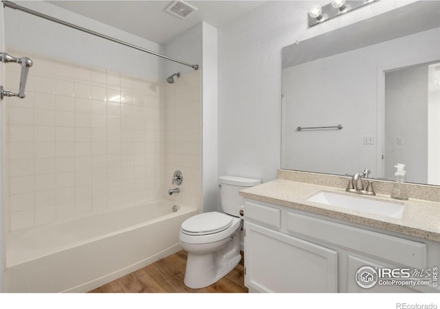 full bathroom featuring hardwood / wood-style flooring, vanity, tiled shower / bath combo, and toilet